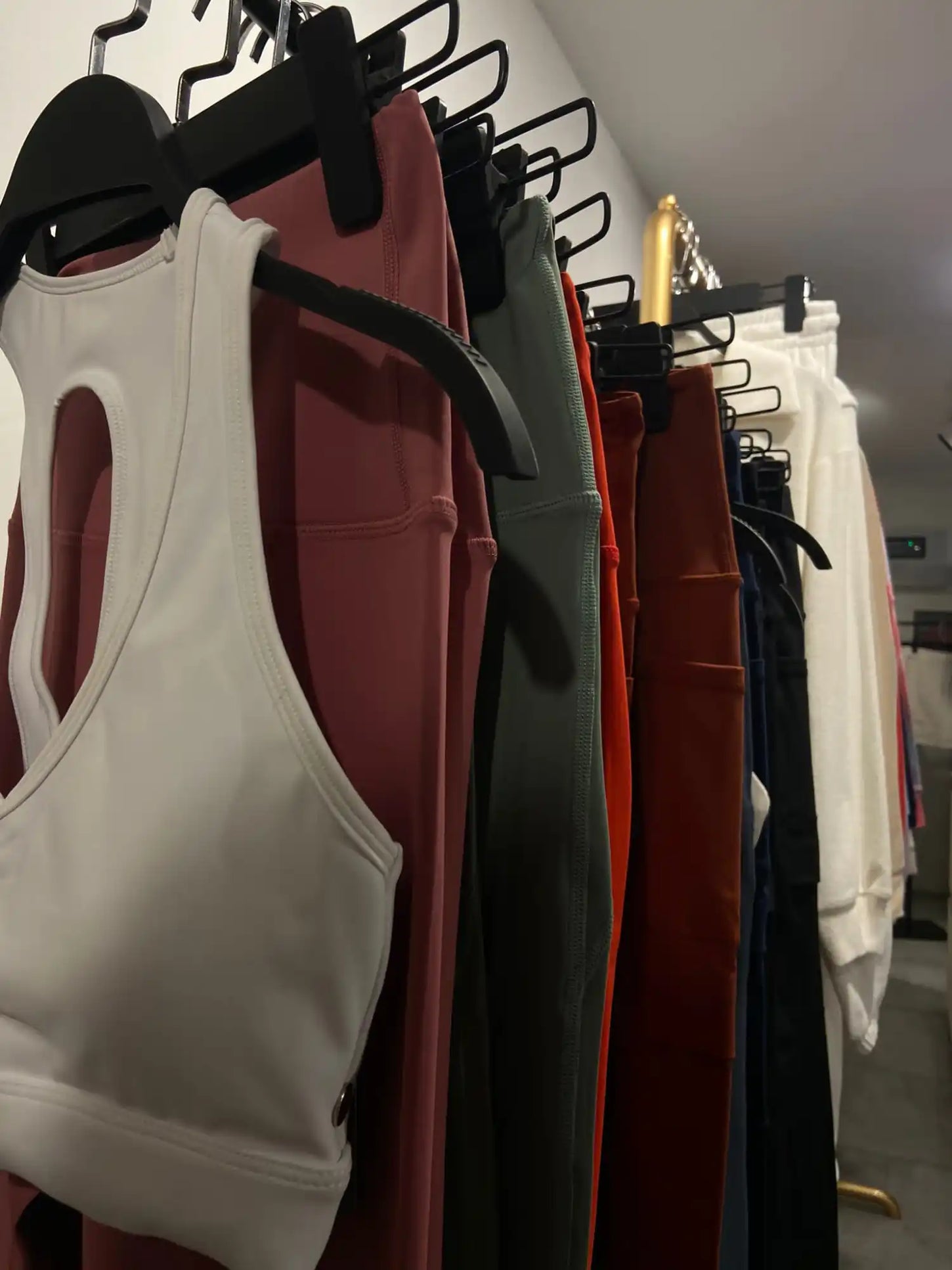 Farklı renklerde, beyaz, bordo ve siyah dahil olmak üzere, kıyafet askılarında asılı atletik formalar veya tişörtler.