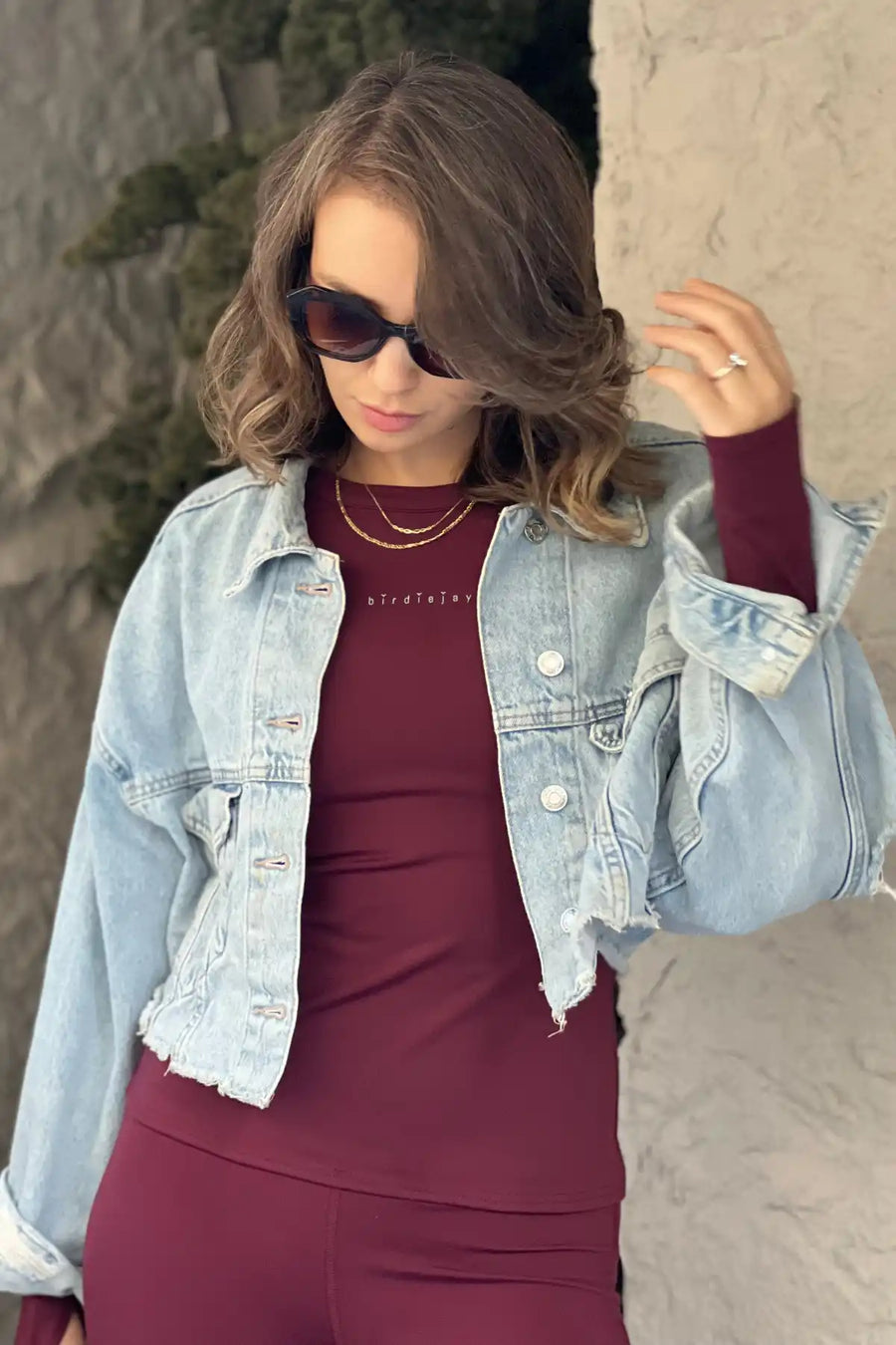 Bordo kıyafet ve kot ceket giymiş kadın.
