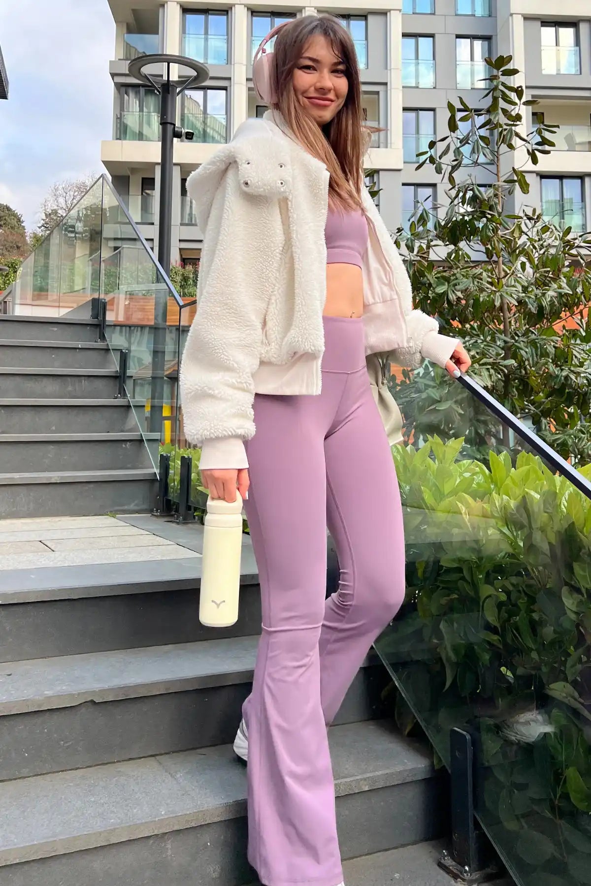 Lila spor seti ve beyaz ceket giymiş kadın.