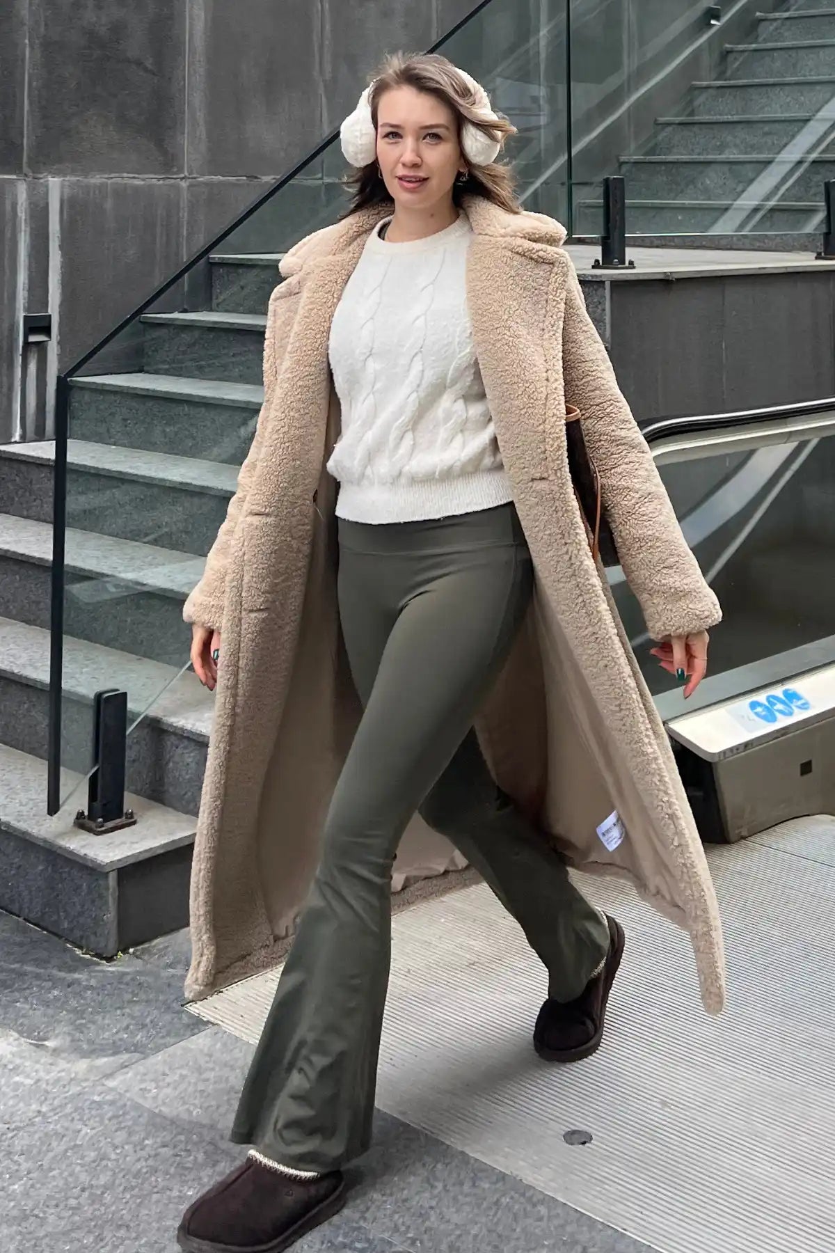 Uzun, bej rengi teddy kaban giymiş kadın.