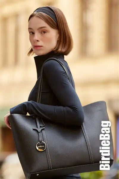 Gümüş aksesuar ve logo ile siyah deri taşıma çantası.